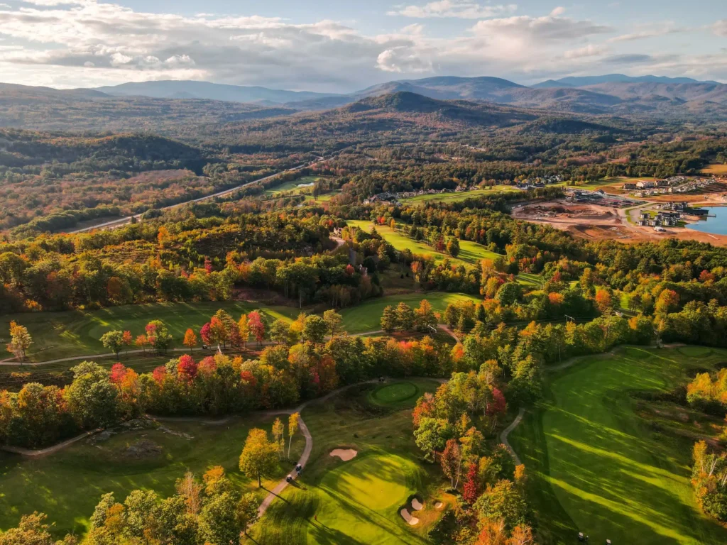 Aerial view of a golf course in autumn showcasing vibrant fall foliage and green fairways.