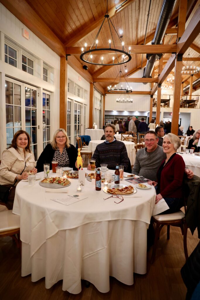 Guests enjoying pizza and drinks at a table during a comedy night at Owl’s Nest Resor