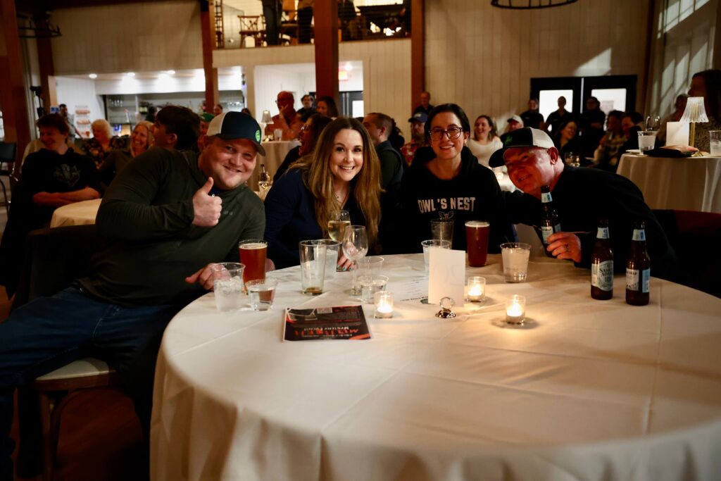 Guests enjoying drinks and conversation at a table during a comedy show at Owl’s Nest Resort