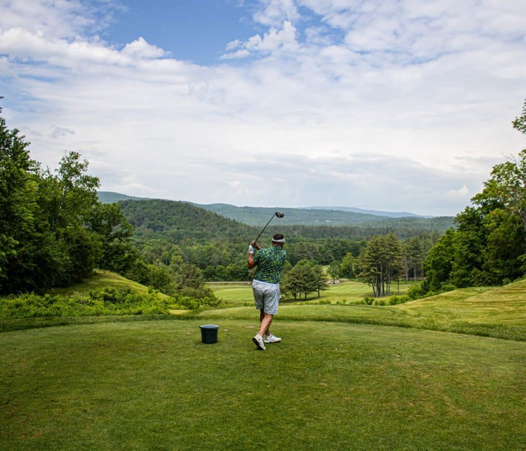Golfer teeing off during the Speare Memorial Golf Tournament at Owl’s Nest Resort in New Hampshire