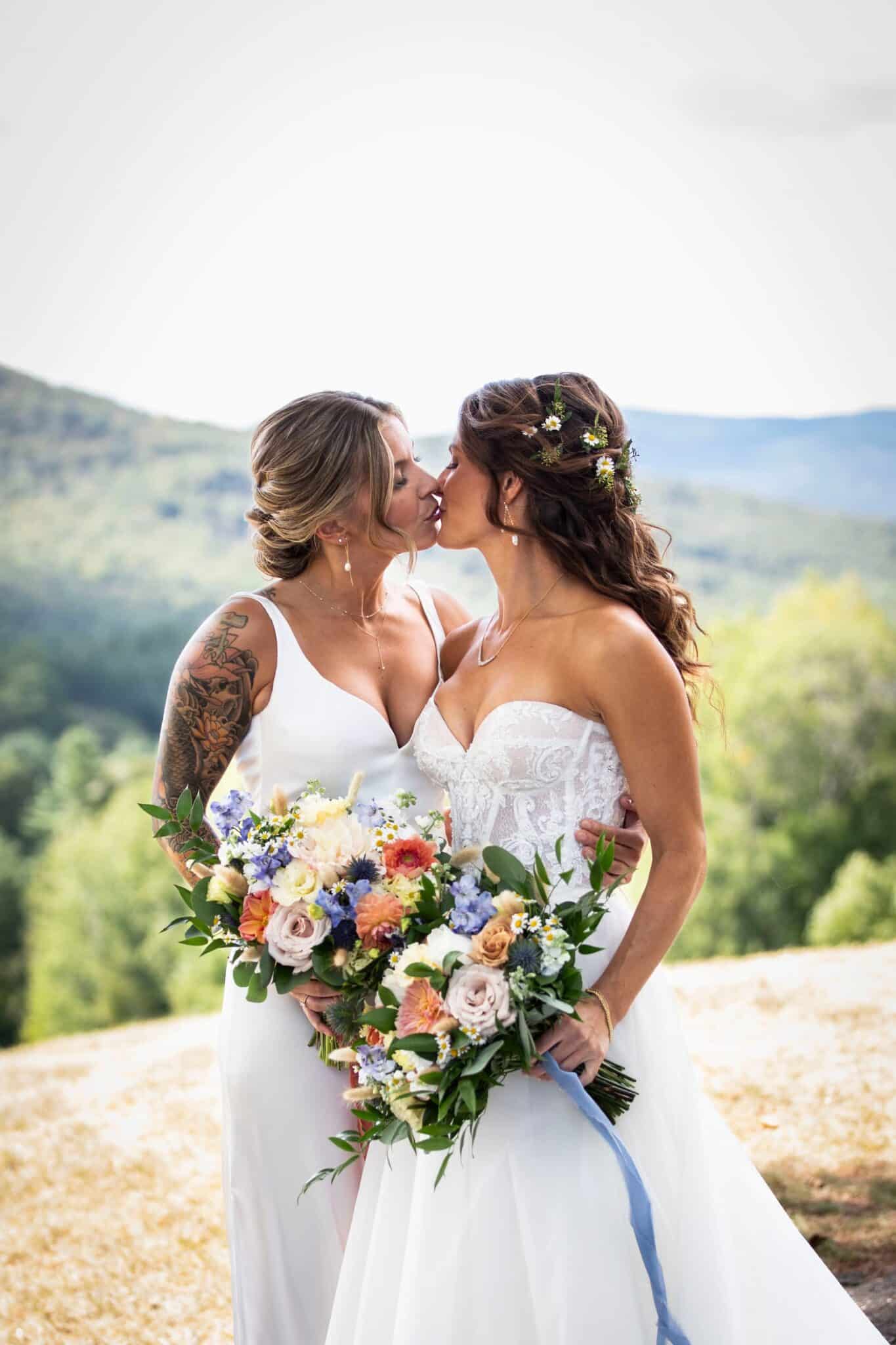 Two brides sharing a kiss during their wedding at Owl's Nest Resort in New Hampshire's White Mountains.