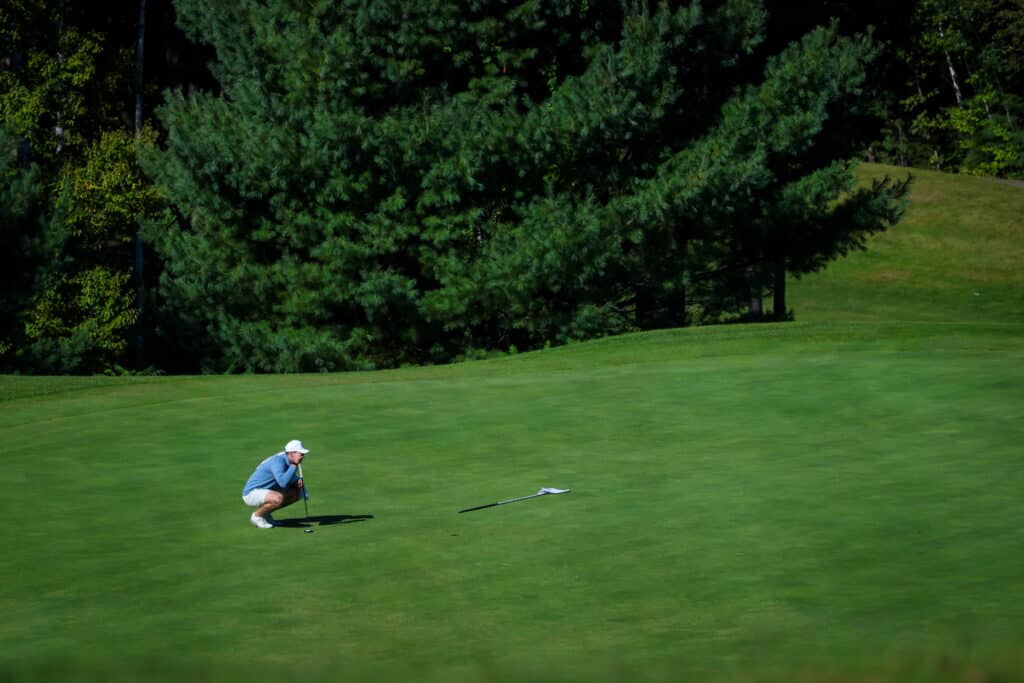 Golfer lining up a putt on the green at Owl’s Nest Resort.