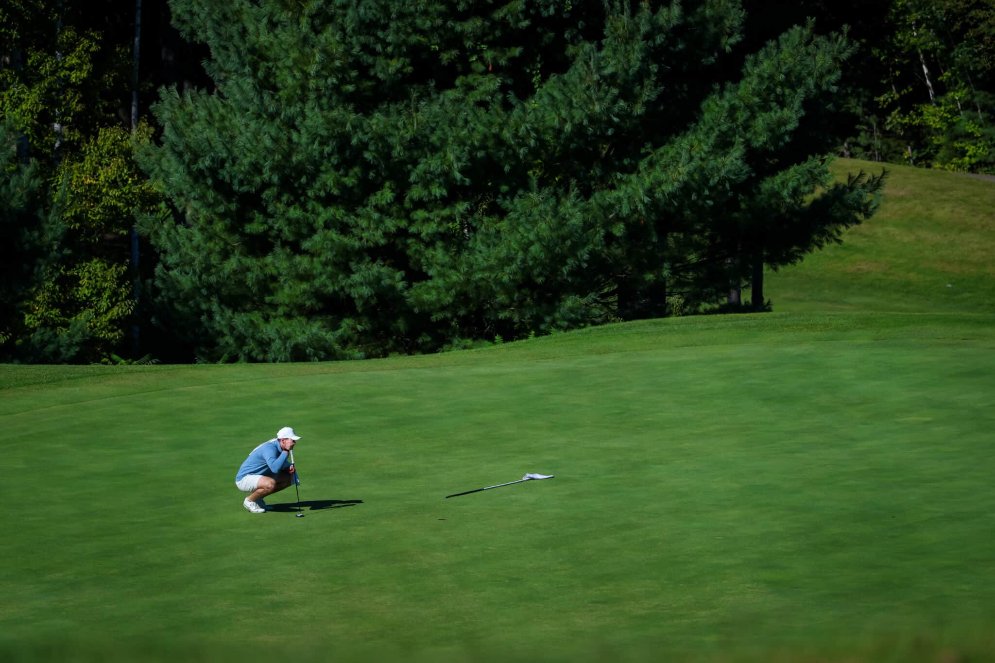 Golfer lining up a putt on the green at Owl’s Nest Resort.